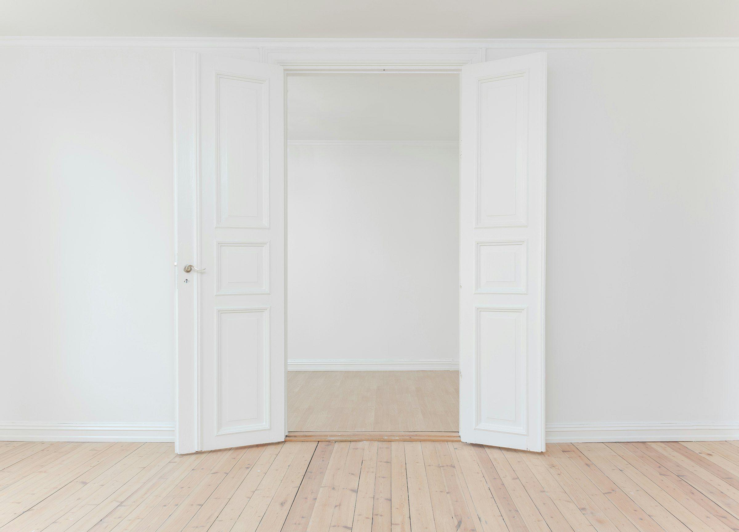 Empty room with pale timber floor and tall doors before installation