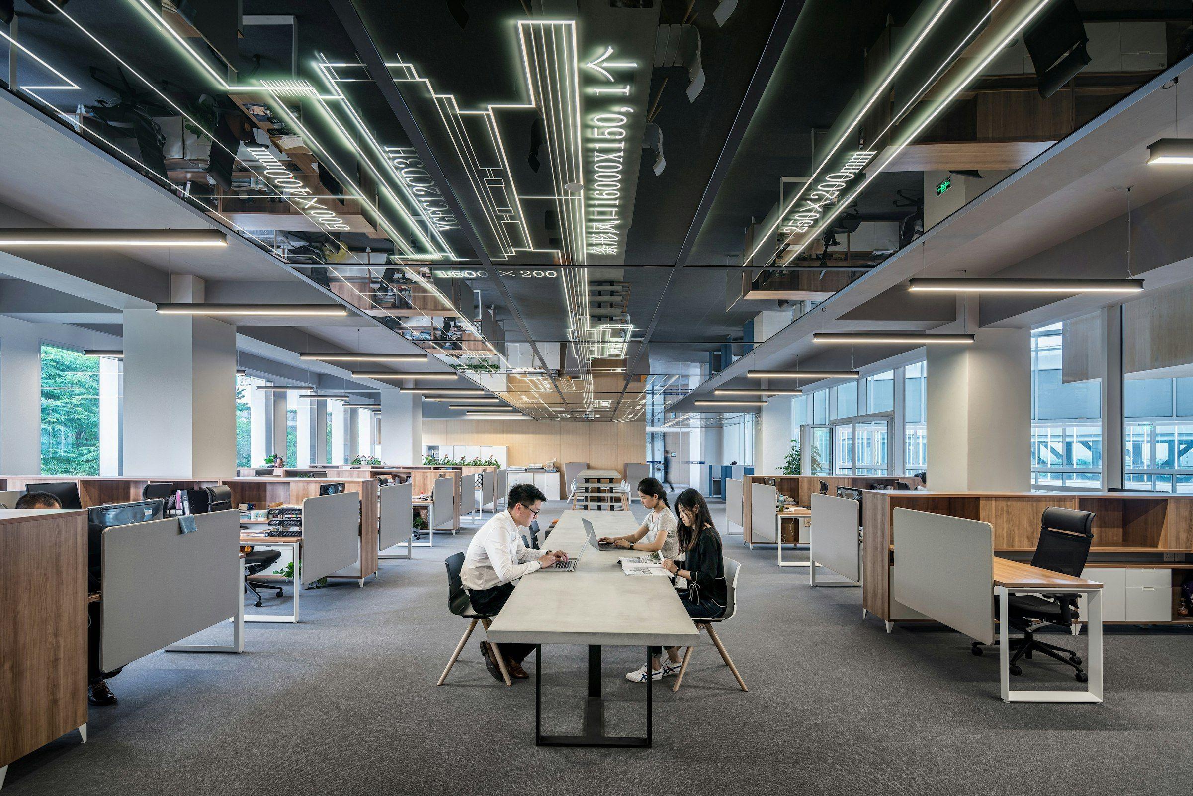 Open-plan office floor with exposed services and long shared worktables