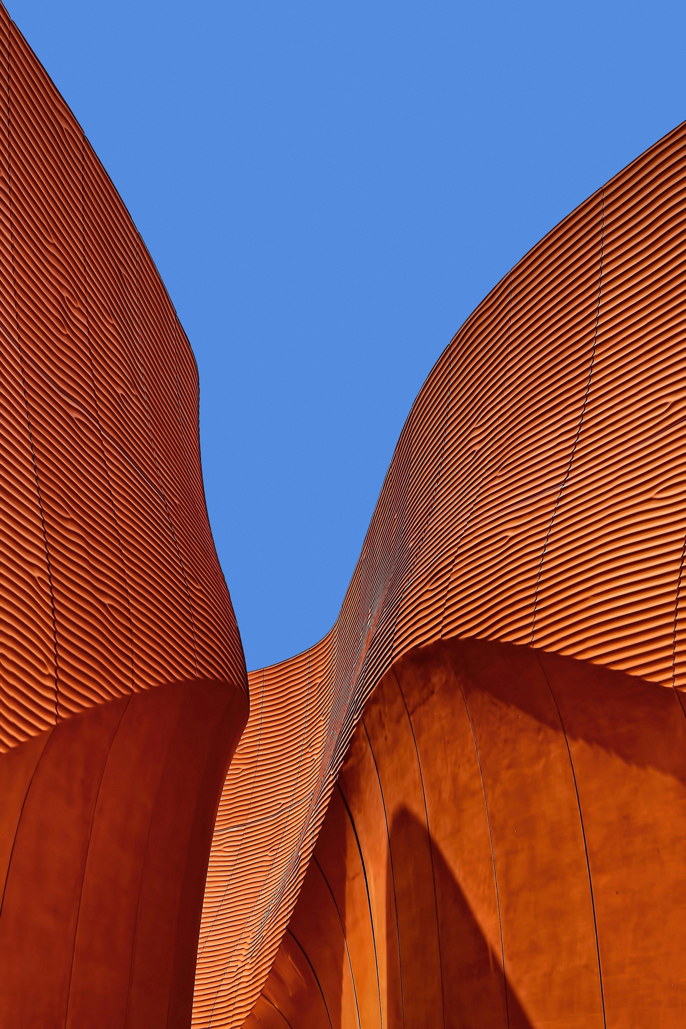 Curved architectural facade in warm terracotta, a reference point for Unit surface studies
