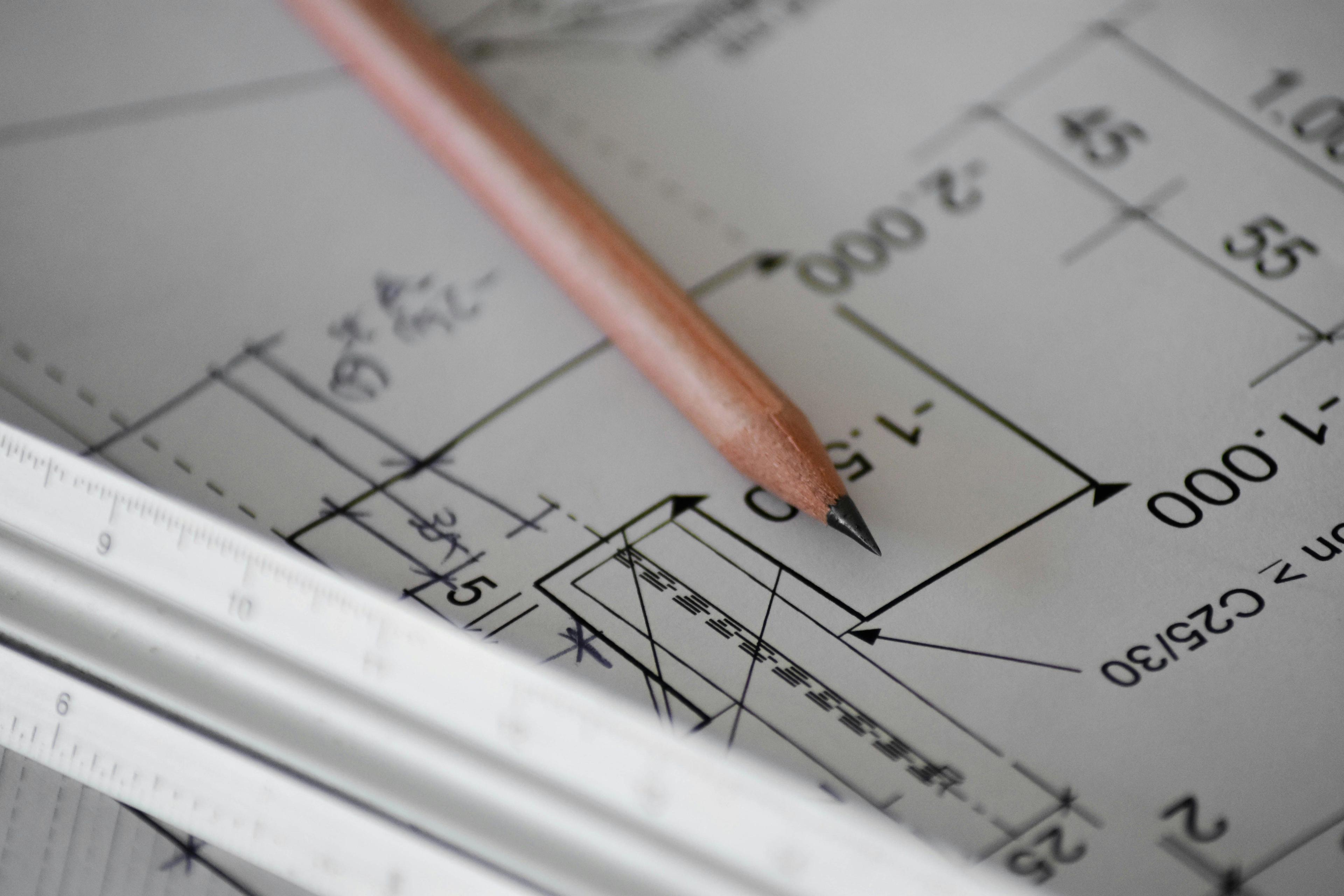 A pencil resting on a dimensioned technical drawing of a Unit component